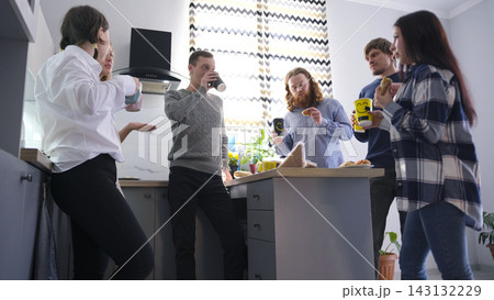 Tired office workers drink coffee and eat sandwiches standing in the cozy office kitchen. Business lunch. Lunch break 143132229