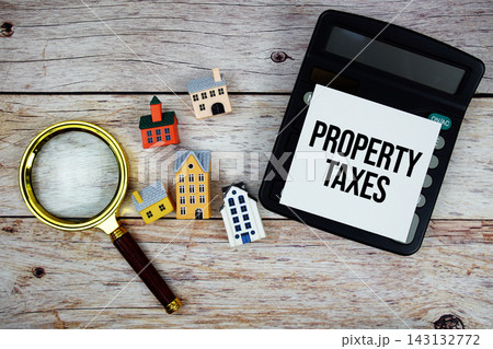 Property Taxes text with house model, calculator and magnifying glass on wooden background Property Taxes text with house model, calculator and magnifying glass on wooden background 143132772