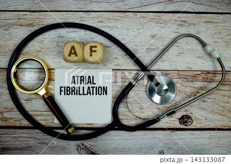 Atrial Fibrillation (AF) text with stethoscope and magnifying glass on wooden background Atrial Fibrillation (AF) text with stethoscope and magnifying glass on wooden background 143133087