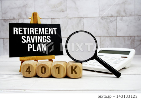 401(k) Retirement Savings Plan text with calculator magnifying glass and on wooden background 143133125