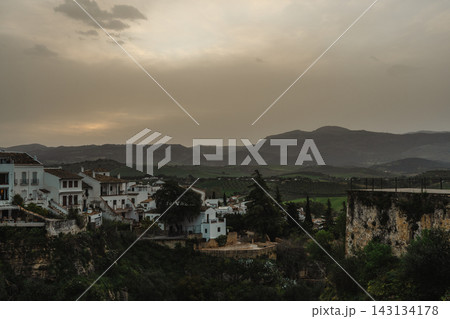 Whitewashed houses on a hillside at dusk with mountains beyond in Ronda, Spain Whitewashed houses on a hillside at dusk with mountains beyond in Ronda, Spain 143134178