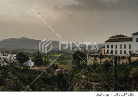 Green Tajo gorge and valley with whitewashed houses and hazy mountains in Ronda, Spain Green Tajo gorge and valley with whitewashed houses and hazy mountains in Ronda, Spain 143134186