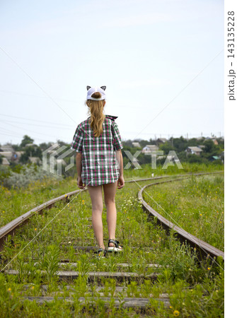 A girl in a plaid shirt walks along old railway tracks A girl in a plaid shirt walks along old railway tracks 143135228