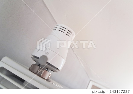 White panel radiator with a thermostatic valve in a minimalist interior, illustrating home heating, temperature control and energy efficiency. Close-up view suitable for home improvement, maintenance  143137227