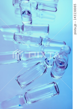 Group of empty glass medical ampoules on blue reflective surface Group of empty glass medical ampoules on blue reflective surface 143138085
