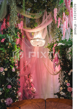 Wooden slab bench surrounded by floral arches and glowing crystal chandelier Wooden slab bench surrounded by floral arches and glowing crystal chandelier 143143370