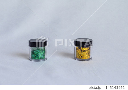 Green and yellow glitter in small containers on white surface Green and yellow glitter in small containers on white surface 143143461