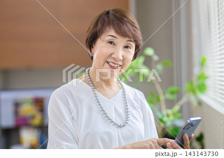オフィスでスマホを見る60代女性 オフィスでスマホを見る60代女性 143143730