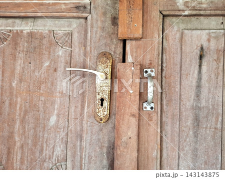 Antique wooden door with ornate corner carvings and tarnished silver metal handle. 143143875
