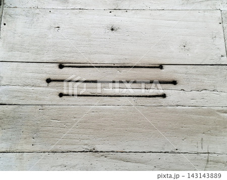 Three black horizontal burnt lines on weathered white painted wooden plank wall. 143143889