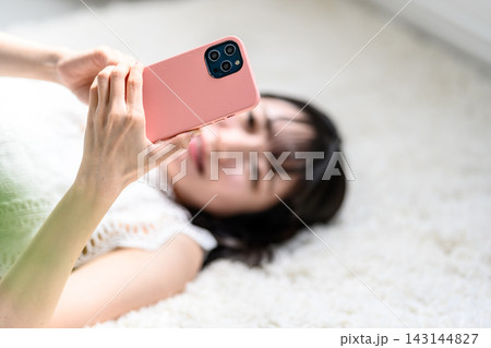 部屋でスマホを操作する女性 143144827