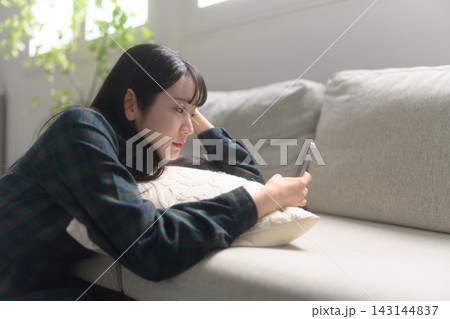 ソファでスマホを見る女性 ソファでスマホを見る女性 143144837