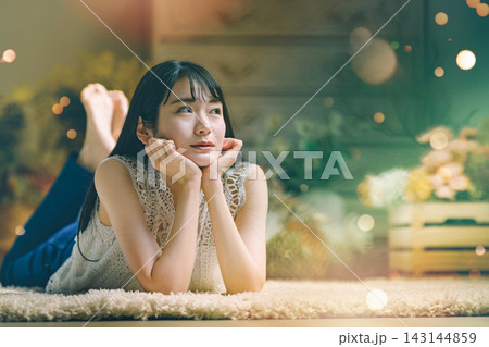 カーペットに寝そべり遠くを見つめる女性 カーペットに寝そべり遠くを見つめる女性 143144859