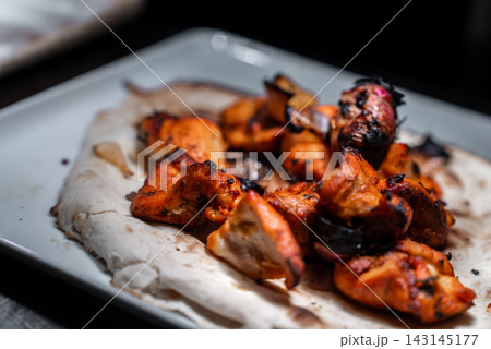 Tandoori grilled chicken on naan under moody indoor lighting Tandoori grilled chicken on naan under moody indoor lighting 143145177
