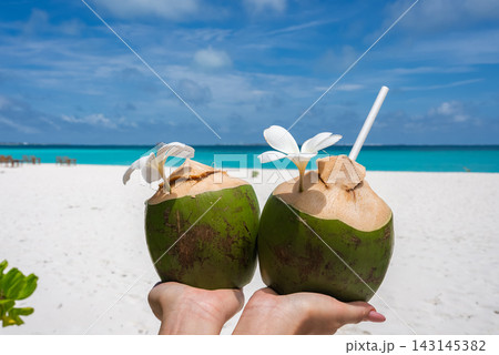 Green coconuts with carved flowers on Maldives white sand beach Green coconuts with carved flowers on Maldives white sand beach 143145382