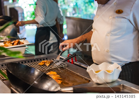 Chef grills fish on teppan griddle at Maldivian resort kitchen Chef grills fish on teppan griddle at Maldivian resort kitchen 143145385