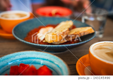 Breakfast table with shakshuka, toasted bread, and coffee 143145490