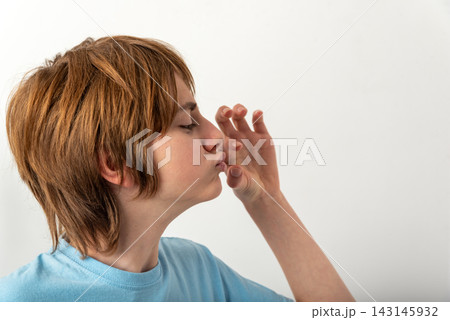 Young boy with eyes closed and puckered lips blowing a kiss toward the camera, playful affectionate gesture in a studio headshot on a clean white background Young boy with eyes closed and puckered lips blowing a kiss toward the camera, playful affectionate gesture in a studio headshot on a clean white background 143145932