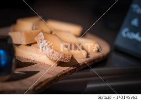 Rind on Alpine cheese sits on a wooden board at San Domenico in Italy. Soft light and shallow focus frame textured edges and a chalkboard sign, evoking apres ski. Rind on Alpine cheese sits on a wooden board at San Domenico in Italy. Soft light and shallow focus frame textured edges and a chalkboard sign, evoking apres ski. 143145962