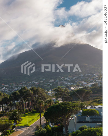 Lion's Head near Cape Town rises behind Atlantic suburbs, billowing clouds skim the summit as sun patches light tree lined streets and modern homes in soft light. Lion's Head near Cape Town rises behind Atlantic suburbs, billowing clouds skim the summit as sun patches light tree lined streets and modern homes in soft light. 143146037