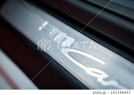 Macro view of Porsche 911 Carrera door sill plate shows embossed 911 and script, polished reflections, angled frame, shallow depth of field, studio lighting. 143146047