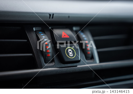 Close interior view shows BMW X5 hazard light triangle, dual seat heater sliders with blue and red LEDs, door lock with green ring, and horizontal air vents. 143146415
