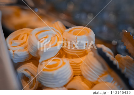 Close up shows piped butter rosettes on a chilled buffet with metal tongs in Oberlech, Austria. Soft cool lighting and shallow depth of field emphasize craft. 143146439