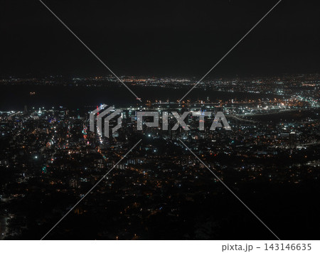 An elevated night view shows Cape Town lit grids, harbor lights, and ocean horizon, with high rises and waterfront, neon accents, ship lights, and long exposure look. 143146635