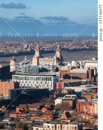 Aerial view of Liverpool, UK at sunrise shows the Royal Liver Building, Port of Liverpool Building, Pier Head offices, the River Mersey, and offshore wind turbines. Aerial view of Liverpool, UK at sunrise shows the Royal Liver Building, Port of Liverpool Building, Pier Head offices, the River Mersey, and offshore wind turbines. 143146975