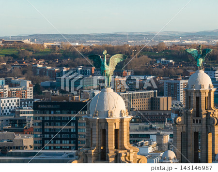 Royal Liver Building twin domes and Liver Bird statues at sunrise in Liverpool, UK. Warm light hits sandstone towers, modern offices, homes, teal patina, and distant hills. Royal Liver Building twin domes and Liver Bird statues at sunrise in Liverpool, UK. Warm light hits sandstone towers, modern offices, homes, teal patina, and distant hills. 143146987