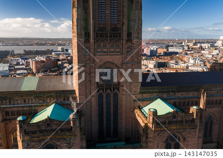 Aerial view of Liverpool, UK, centered on Liverpool Cathedral with rose and lancet windows, green copper chapels, River Mersey left, cranes and wind turbines at sunrise. Aerial view of Liverpool, UK, centered on Liverpool Cathedral with rose and lancet windows, green copper chapels, River Mersey left, cranes and wind turbines at sunrise. 143147035