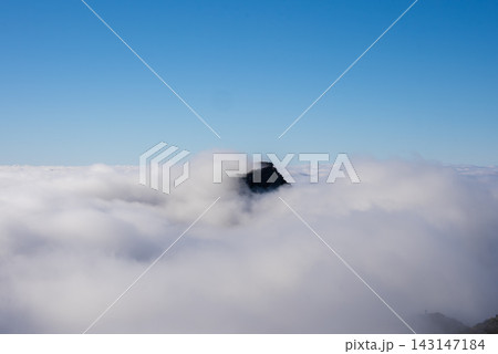 A jagged peak rises through a thick cloud inversion at Pico do Arieiro, Madeira, Portugal. Soft daylight and minimal composition emphasize altitude and isolation. 143147184
