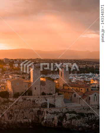 Aerial dusk scene in Antibes, France shows Musee Picasso and Chateau Grimaldi on the rocky waterfront, Old Town roofs, and Port Vauban marina with yachts under warm light. Aerial dusk scene in Antibes, France shows Musee Picasso and Chateau Grimaldi on the rocky waterfront, Old Town roofs, and Port Vauban marina with yachts under warm light. 143148371