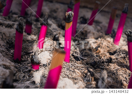 Close up of pink incense sticks burning in ash at Sensoji in Tokyo. Thin smoke rises as visitors take part in a ritual for purification and prayers. Close up of pink incense sticks burning in ash at Sensoji in Tokyo. Thin smoke rises as visitors take part in a ritual for purification and prayers. 143148432