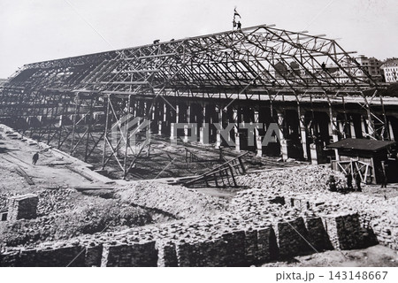 Workers stand on trusses of a pavilion under construction in Riga, Latvia. Black and white, wide composition, deep shadows, early 20th century industrial build. 143148667