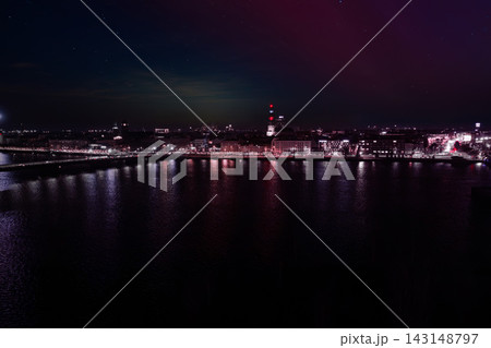 Riga Daugava riverfront at night shows magenta and violet aurora lights, Riga TV Tower beacons, and 11. novembra krastmala during Staro Riga 2025 and Independence Day Riga Daugava riverfront at night shows magenta and violet aurora lights, Riga TV Tower beacons, and 11. novembra krastmala during Staro Riga 2025 and Independence Day 143148797