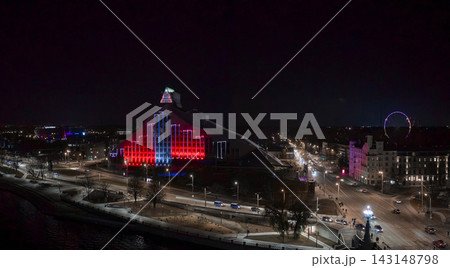 Aerial night view of Latvian National Library by Daugava River in Riga, Latvia. Vertical red and white lights, traffic glow, ferris wheel, festival celebrations present. Aerial night view of Latvian National Library by Daugava River in Riga, Latvia. Vertical red and white lights, traffic glow, ferris wheel, festival celebrations present. 143148798