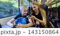 Smiling teenage girl and young boy using smartphones while traveling on a train 143150864