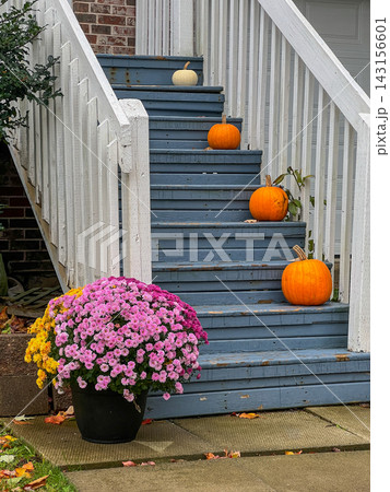 Autumn porch entrance decorated with pumpkins and seasonal chrysanthemums on wooden stairs 143156601