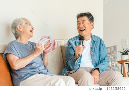 家のリビングでカラオケを楽しむ笑顔のシニア夫婦 家のリビングでカラオケを楽しむ笑顔のシニア夫婦 143158422