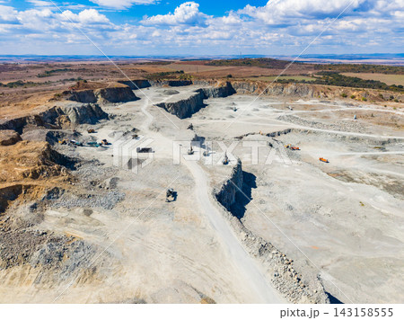 Granite quarry operation showing machinery and extraction site in a dry, open landscape under a clear blue sky 143158555