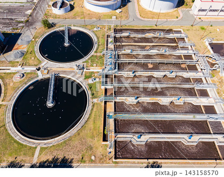 Wastewater treatment facility in operation with multiple tanks and equipment during daytime Wastewater treatment facility in operation with multiple tanks and equipment during daytime 143158570
