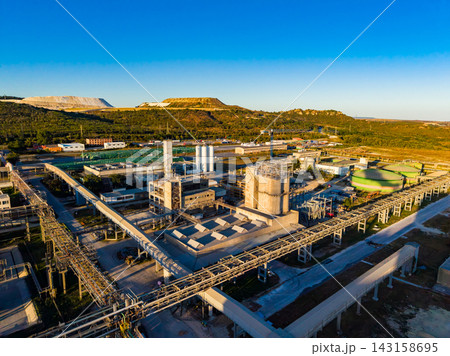 Industrial site with processing facilities and pipelines located in a countryside area during daytime under a clear blue sky 143158695