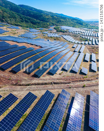 Solar panel farm in open area showing rows of solar panels under clear sky with distant hills in background Solar panel farm in open area showing rows of solar panels under clear sky with distant hills in background 143158706