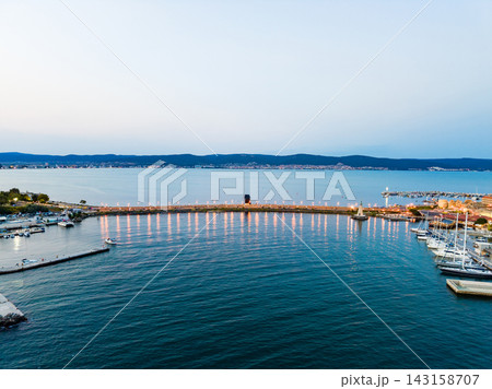 Evening view of a marina and waterfront area during sunset in a coastal town by the sea 143158707