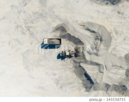 Work taking place at a granite quarry with machinery moving and transporting materials on the ground 143158731