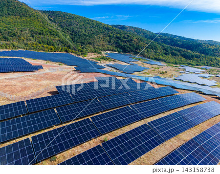 Solar panel installation in a field on a sunny day surrounded by hills in a rural area 143158738