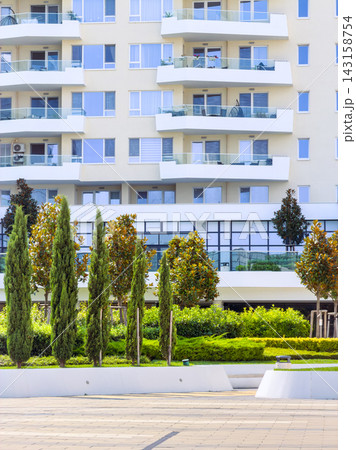 Green landscaping in front of modern apartment building during daytime with clear sky 143158754