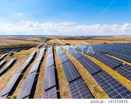 Solar panels cover a large area in a renewable energy farm near a rural landscape under a clear blue sky Solar panels cover a large area in a renewable energy farm near a rural landscape under a clear blue sky 143158838