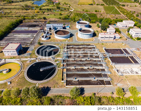 Wastewater treatment facility in operation with various processing tanks in a landscape setting 143158851